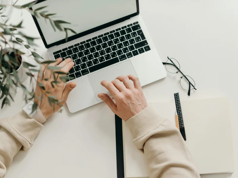 La mano de una persona utilizando una computadora portátil mientras trabaja en un empleo online.