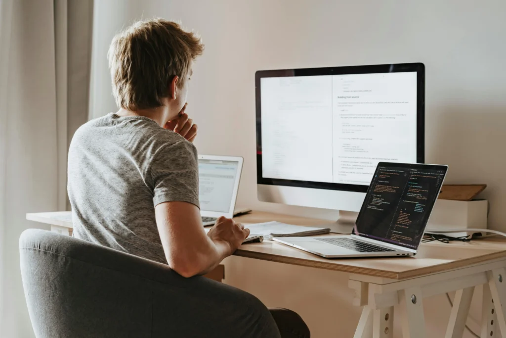 Hombre programando desde casa en un rol de trabajo remoto frente a su computadora portátil