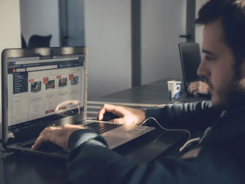 Hombre trabajando en su computadora portátil, redactando su currículum vitae con concentración en Cuba